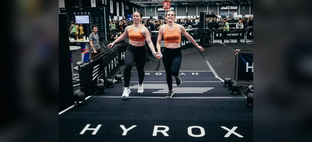 Deux adhérentes de Farmer CrossFit Plaisir franchissent la ligne d'arrivée d'une compétition HYROX